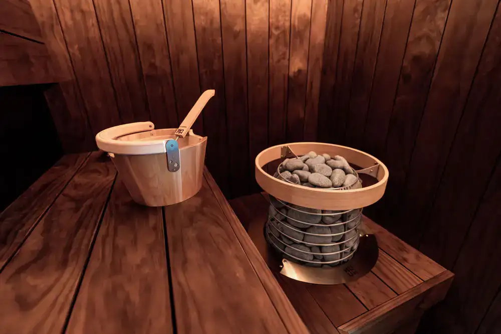 Steam rising off hot sauna stones in a dim wooden room